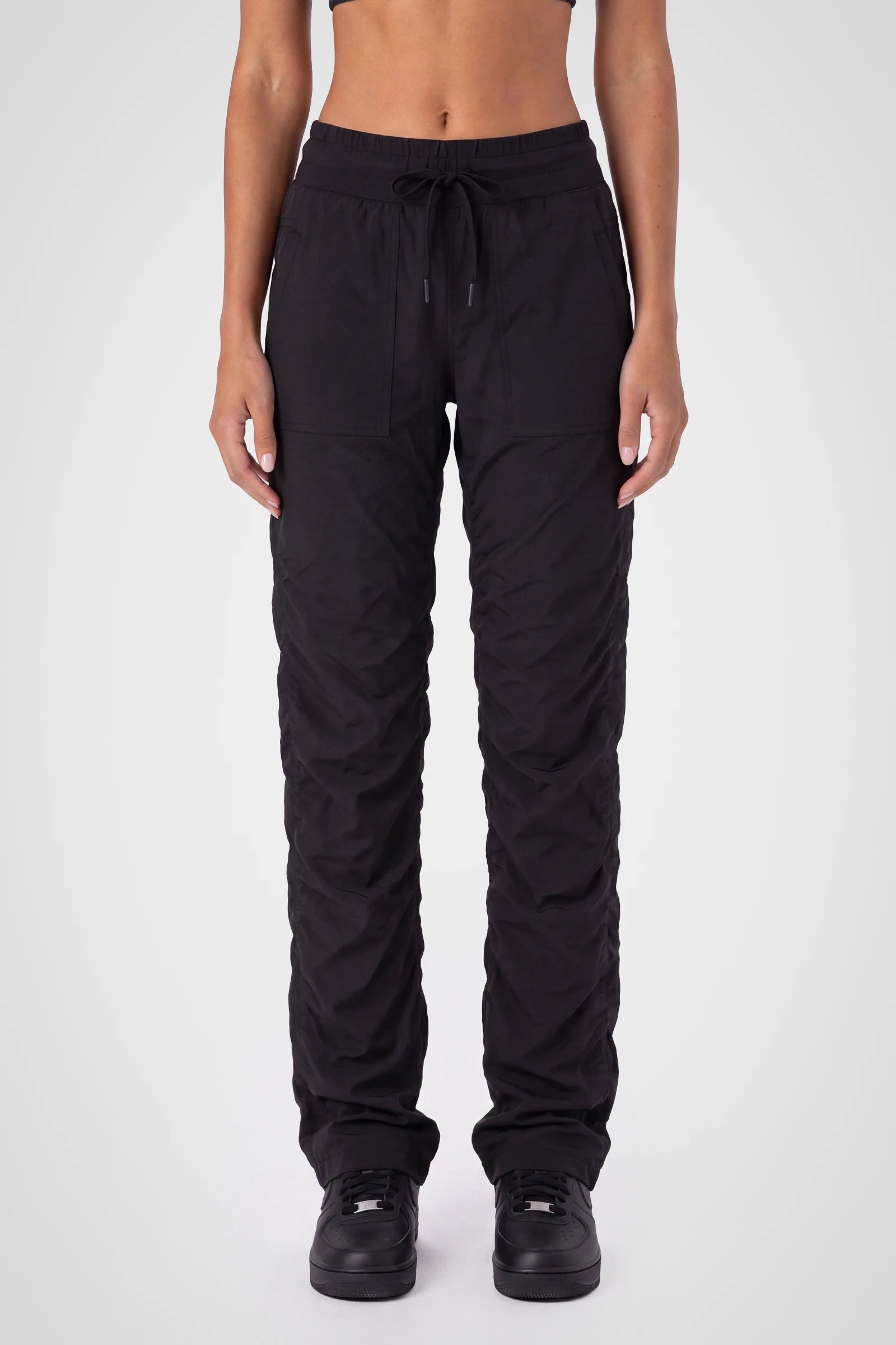 Women’s Black Adventurous Pant, front close-up showing the elastic drawstring waistband, oversized patch pockets and gathered cuffs.