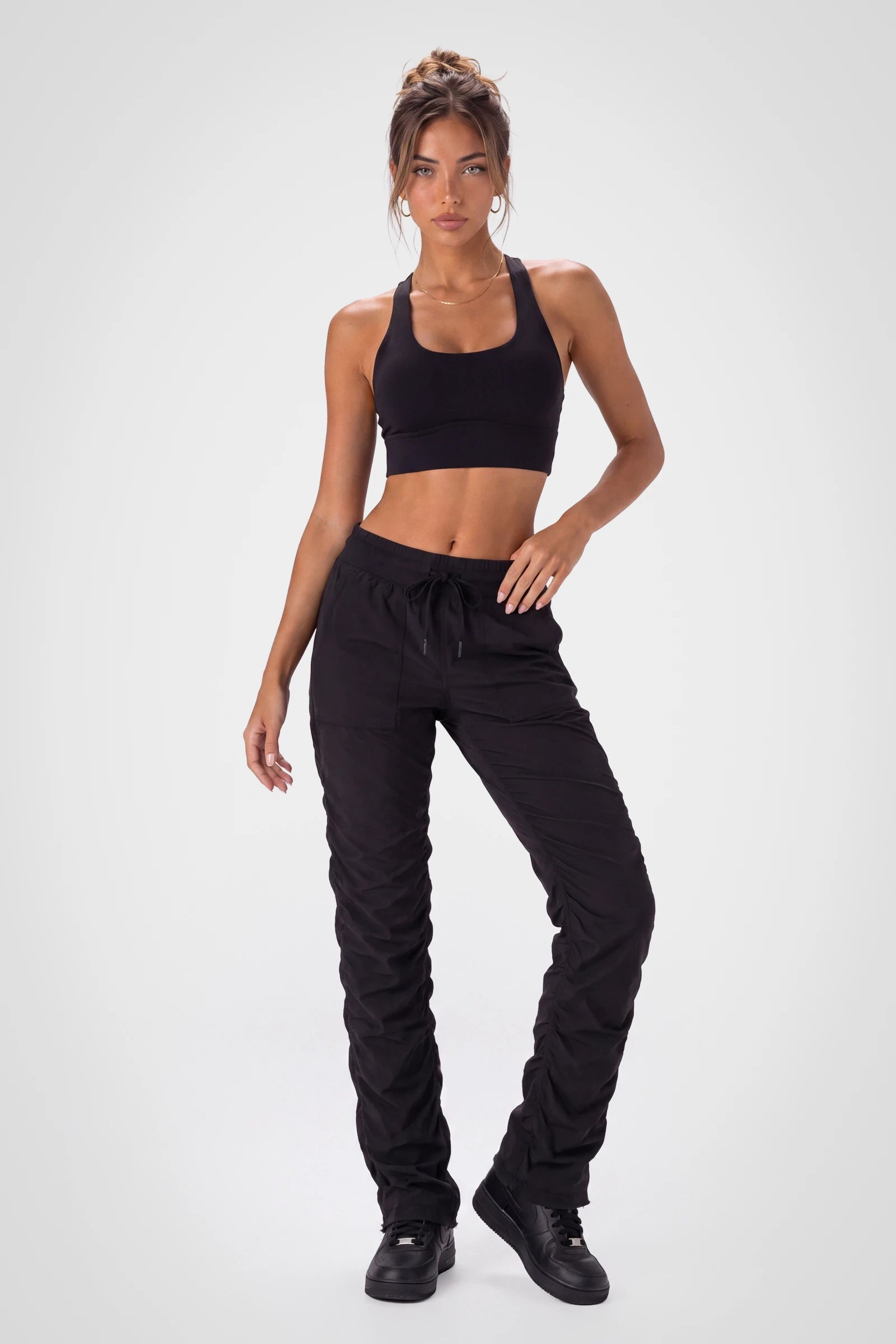 Women’s Black Adventurous Pant, three-quarter side studio view showing the relaxed tapered leg, side patch pocket and gathered cuff.